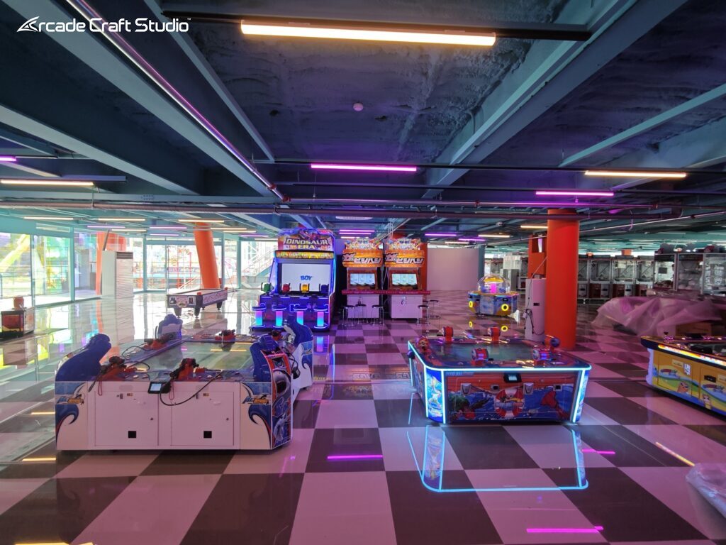 Large distributor-scale arcade fit-out in Korea with air-hockey tables, kiddie shooter cabinets and redemption machines on a checkerboard floor, some units still plastic-wrapped before opening